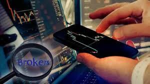 Persona usando un portátil y un móvil para elegir un bróker para invertir.